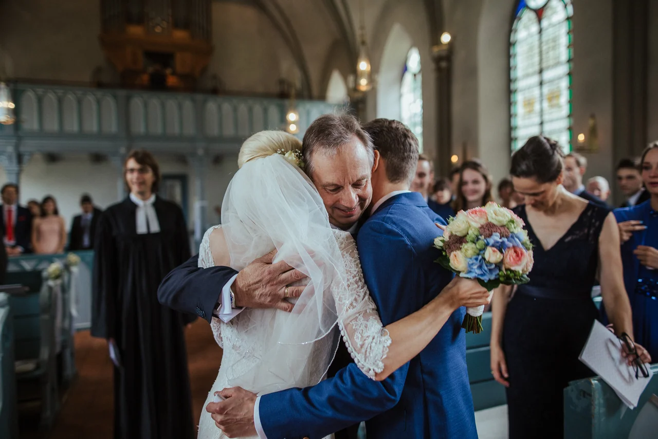Emotionale Umarmung von Braut und Vater nach der Trauung