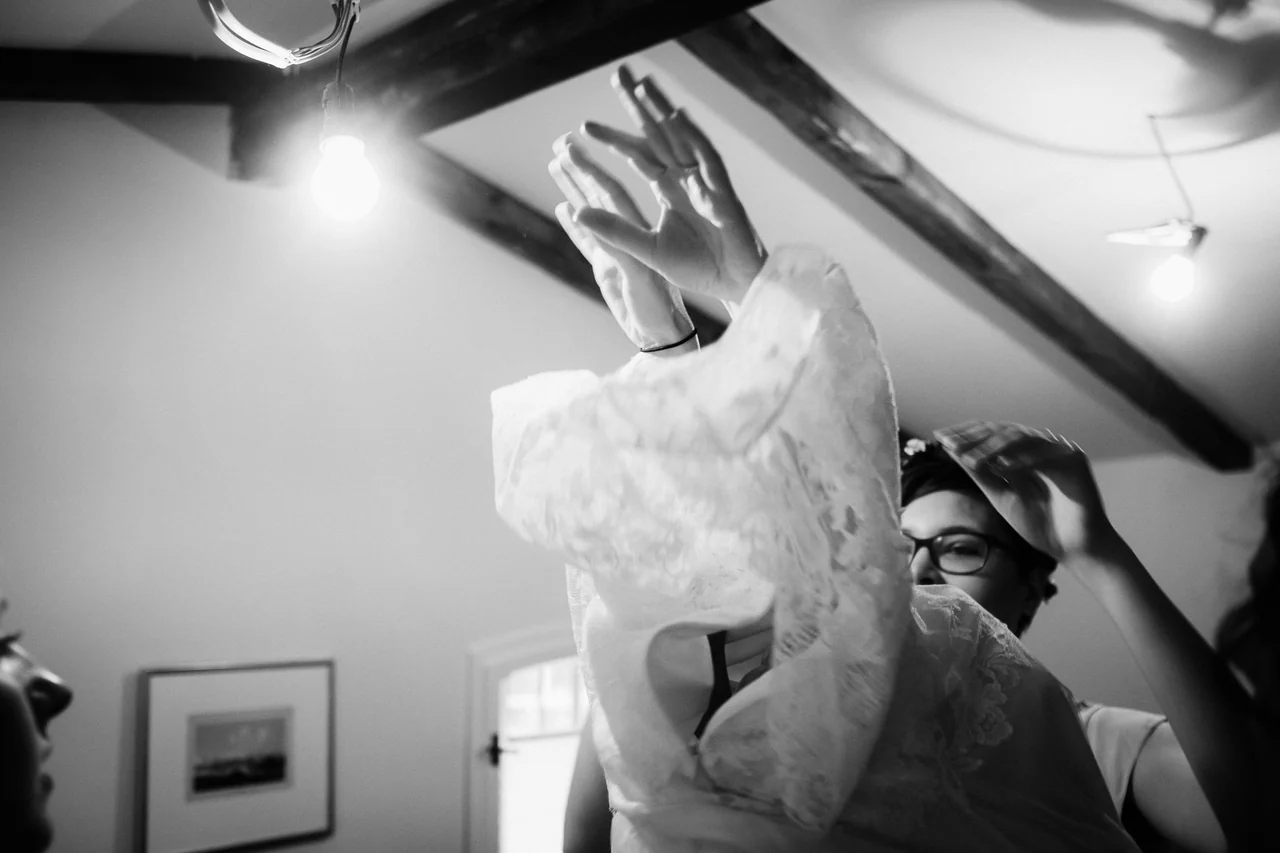 Braut wird beim Getting Ready in ihr Hochzeitskleid geholfen